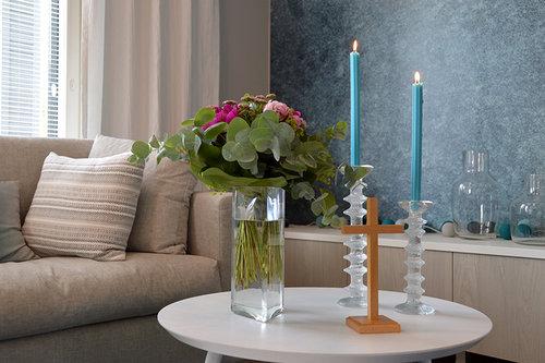 Koti, olohuoneen pöydällä on kukkia ja kynttilöitä sekä risti. Kuva: Kirkon kuvapankki 