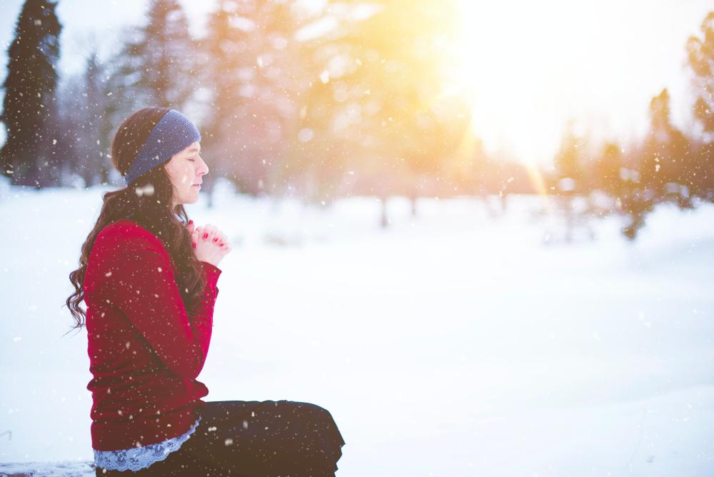 Nainen rukoilee lumisessa säässä. Kuva Ben White, Unsplash