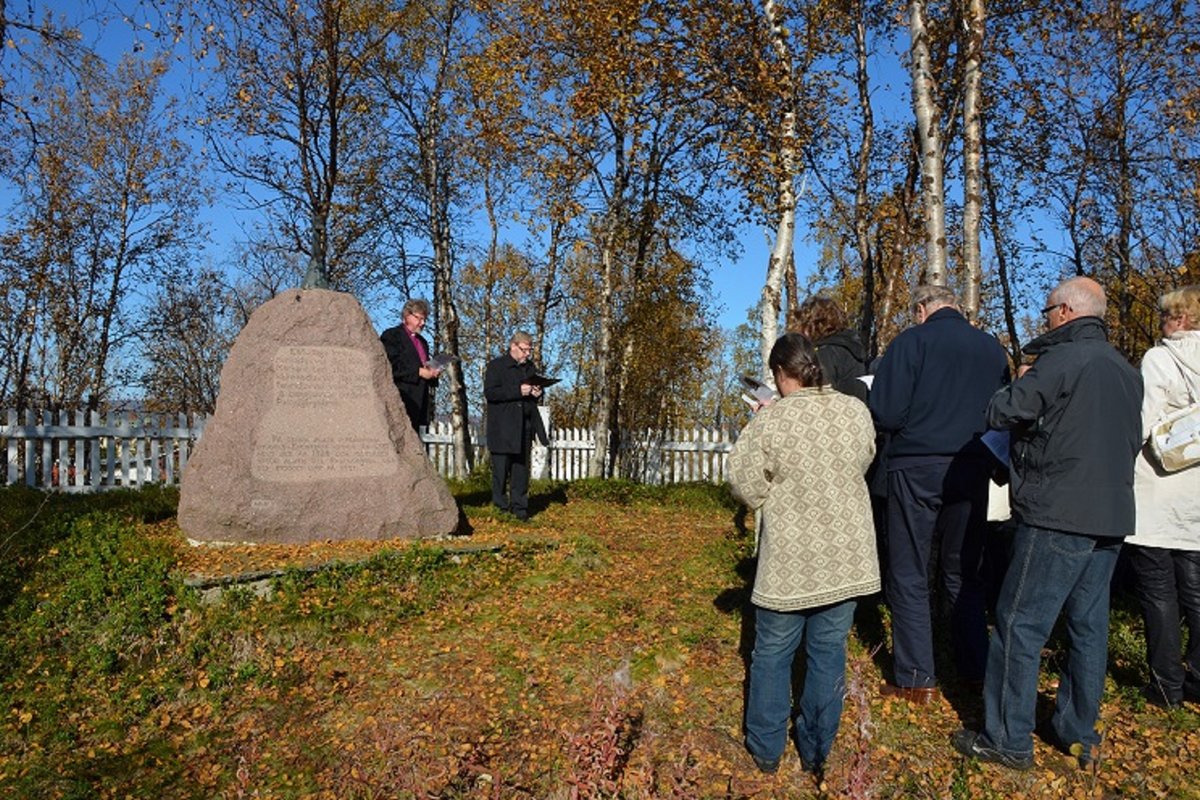 Piispa pitää hartautta Markkinan kirkon muistokiven luona, läsnä seurakuntalaisia
