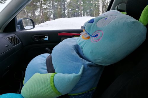 Iso sininen pehmolelu, Mörri nimeltään, istuu auton etupenkillä turvavöissä valmiina lähtemään kerhoon.